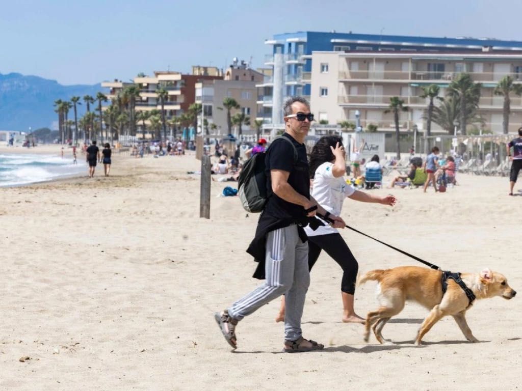 Pareja paseando a su perro en la playa de Ponent en Salou